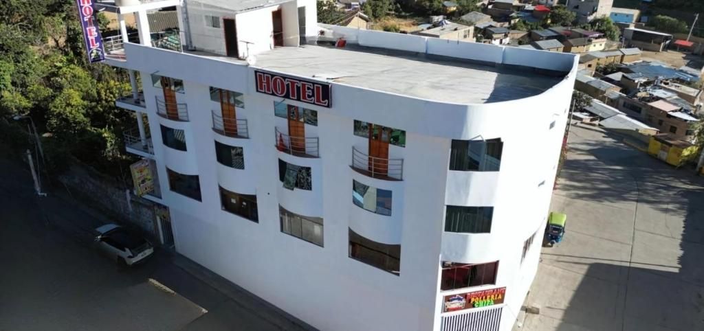 A multi-story hotel with a flat roof, several balconies, and a sign indicating it is a hotel.