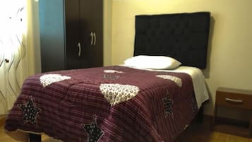 A bedroom with a bed, a wardrobe, and a nightstand.