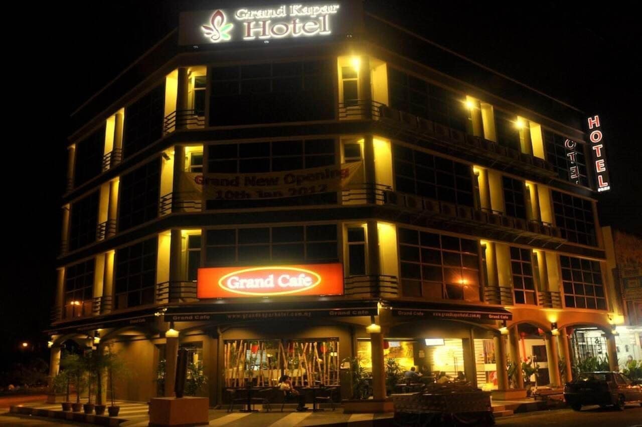 A hotel with a prominent Grand Cafe sign, multiple balconies, and a well-lit facade.