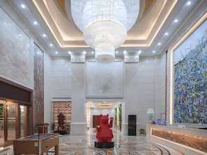 A spacious lobby with a large chandelier, a reception desk, and a red sculpture. - Campanile Hotel (Shenzhen)