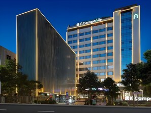 A modern hotel with a prominent 'Camparile' sign, featuring a tall building with a glass facade and a shorter adjacent structure with vertical lines. - Campanile Hotel (Shenzhen)