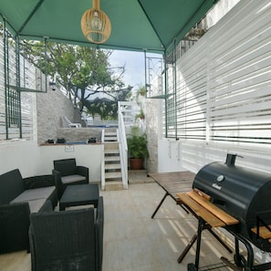 An outdoor patio area with wicker furniture, a barbecue grill, and a staircase leading to a pool. - Posada J & J Forbes (San Andrés)