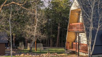 A cabin with a wooden exterior, a balcony, and a surrounding forested area.