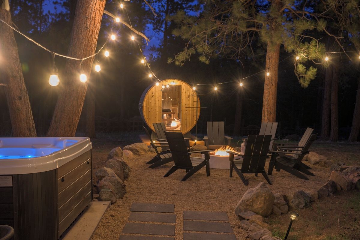 A cozy outdoor seating area with a hot tub, fire pit, and string lights.