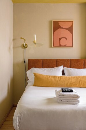A hotel room with a bed, pillows, a wall-mounted lamp, and a framed artwork. - The Friendship Ranch: Mid-Century A-Frame, Hot Tub & Sauna (Bailey)