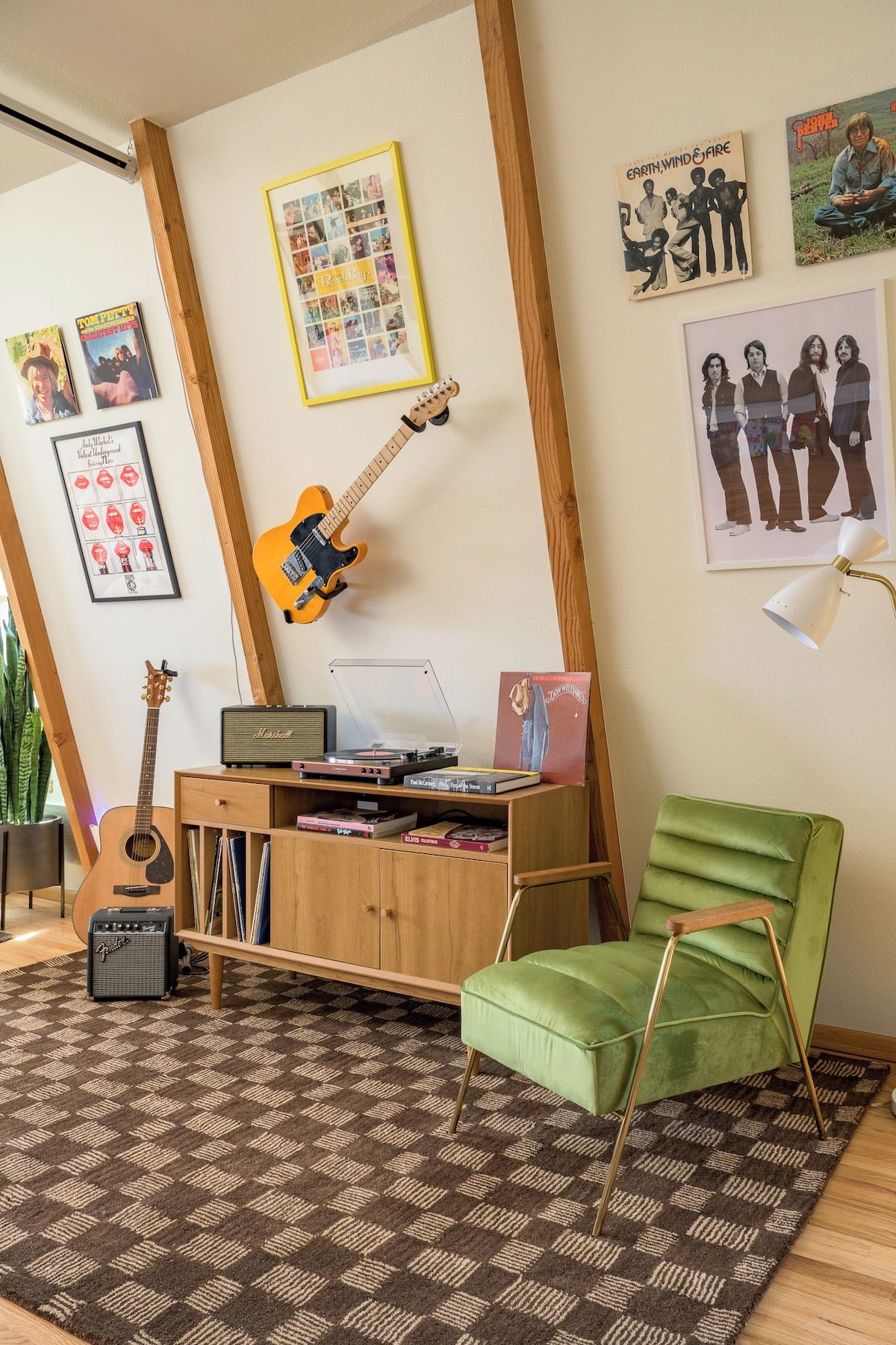 A room with a guitar, a record player, and a green chair.