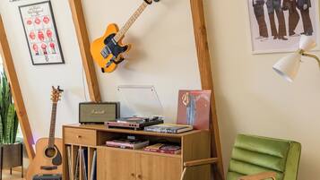 A room with a guitar, a record player, and a green chair.