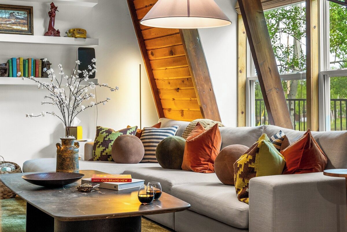 A cozy living room with a sofa, cushions, a coffee table, and a vase with branches.