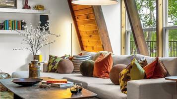 A cozy living room with a sofa, cushions, a coffee table, and a vase with branches.