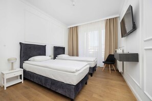 Ein Hotelzimmer mit zwei Betten, einem Fernseher, einem Schreibtisch und einem Sessel.