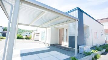 A modern house with a covered porch, a front door, and a small garden area.