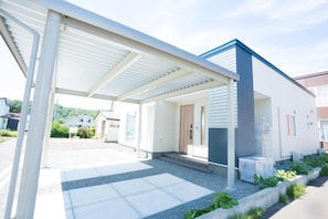 Una casa moderna con un porche cubierto, puerta principal y un pequeño jardín.