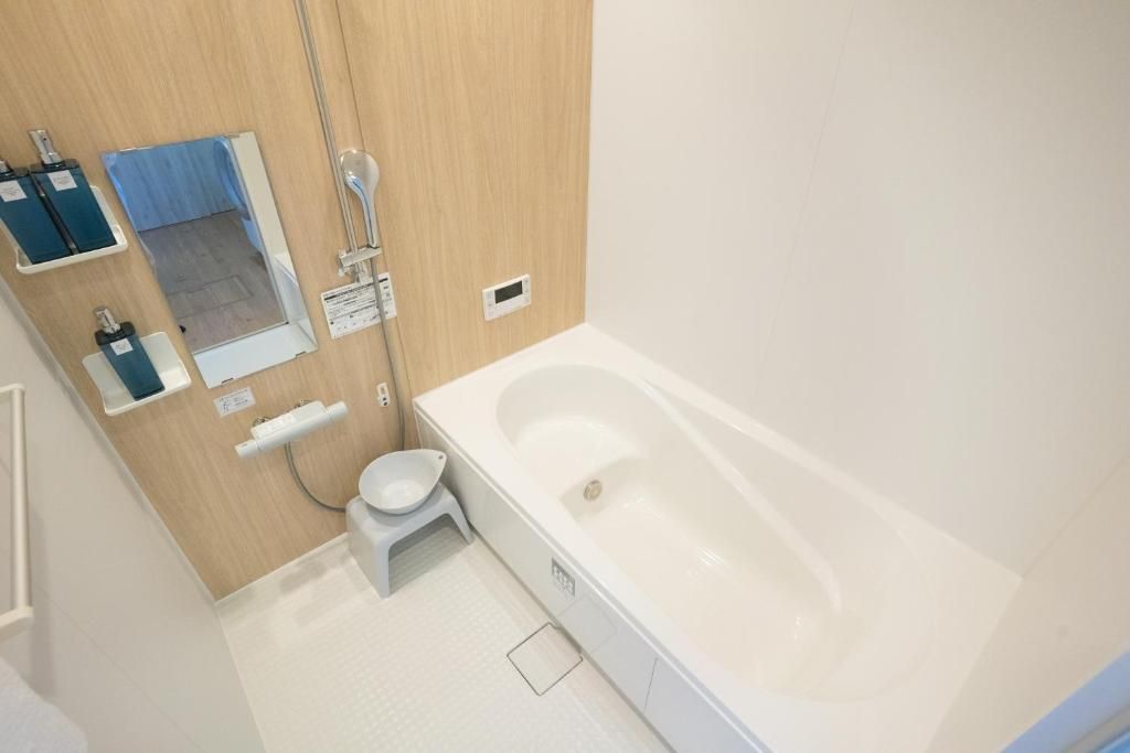 A bathroom with a bathtub, a toilet, a shower, and a mirror.