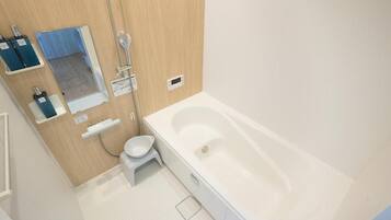 A bathroom with a bathtub, a toilet, a shower, and a mirror.