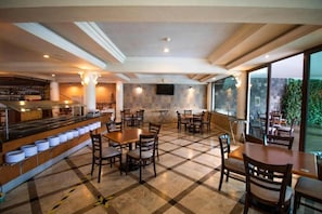 Un restaurante con barra, varias mesas y sillas.