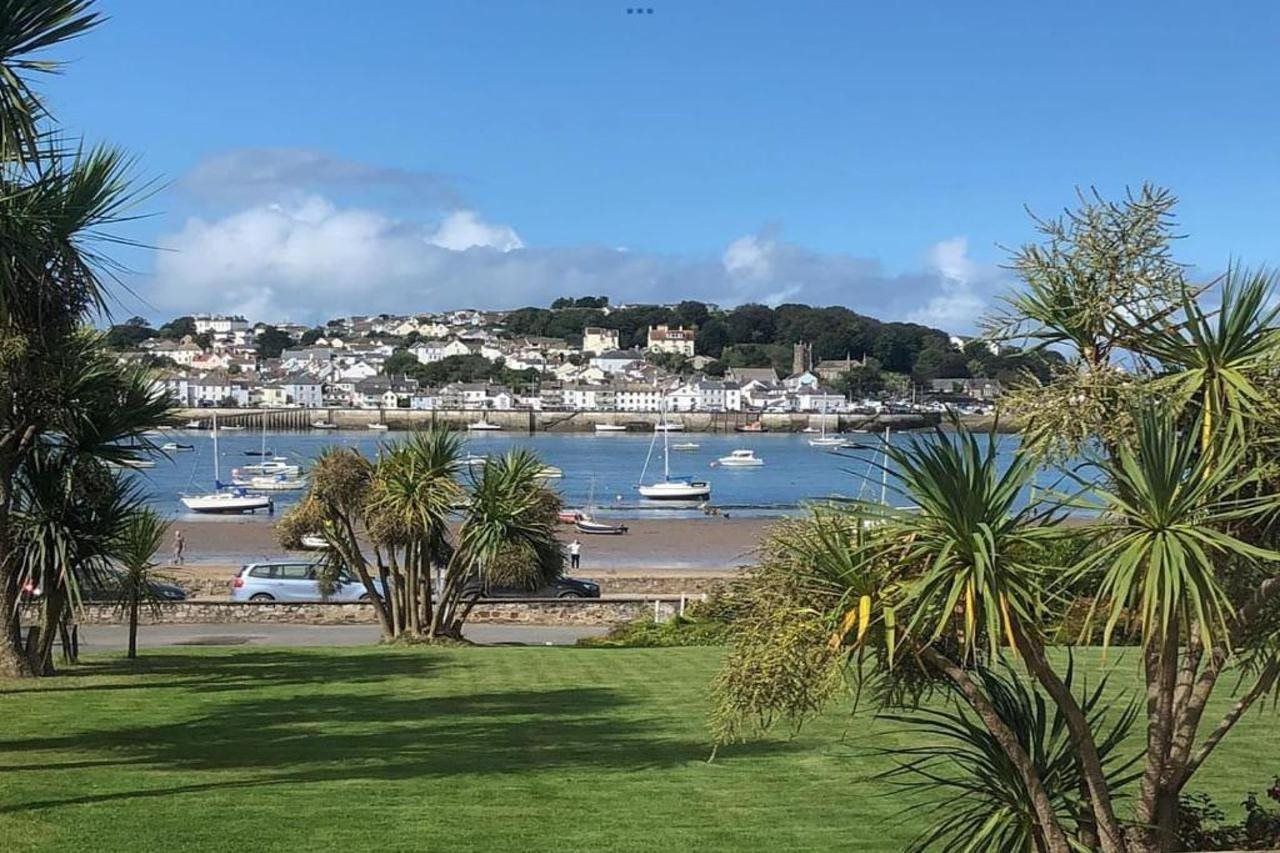 A coastal town with boats docked at a marina, a beach, and a hill with buildings.