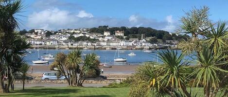 A coastal town with boats docked at a marina, a beach, and a hill with buildings.