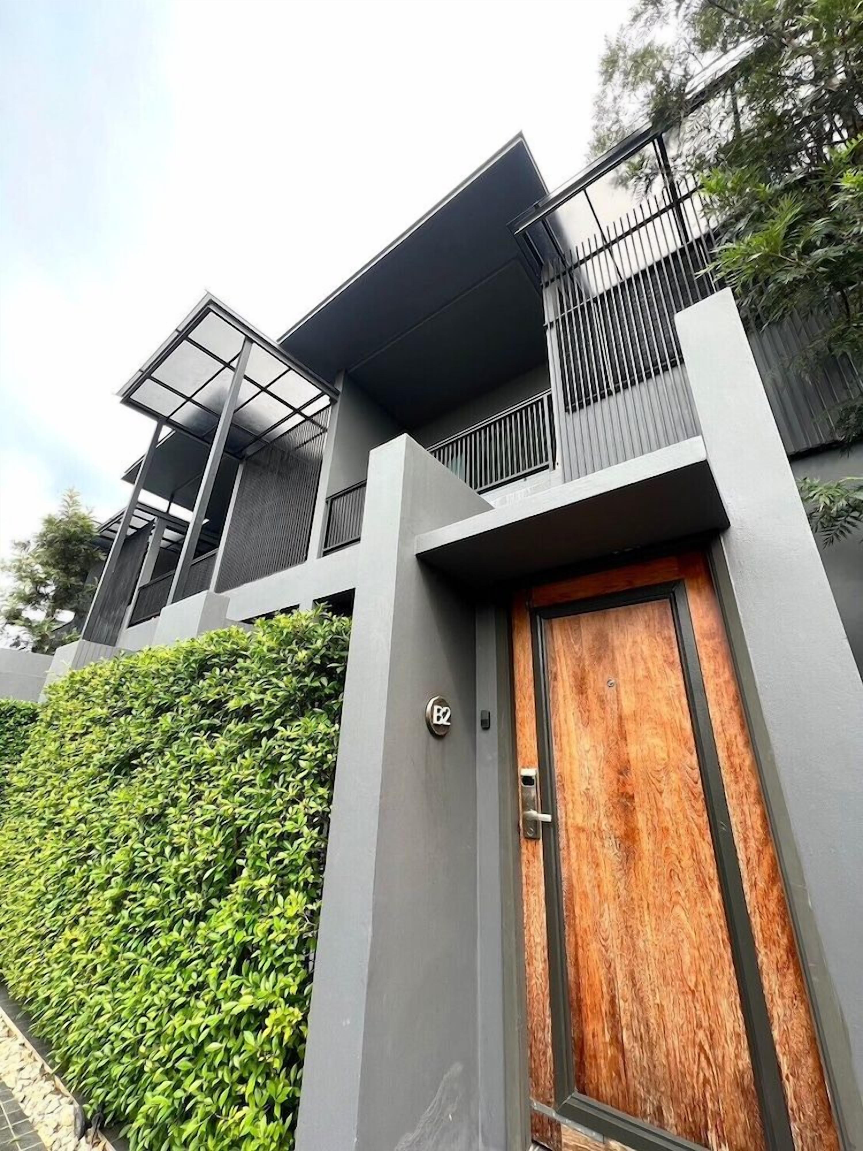A modern building with a grey facade, a wooden door, and a metal gate.