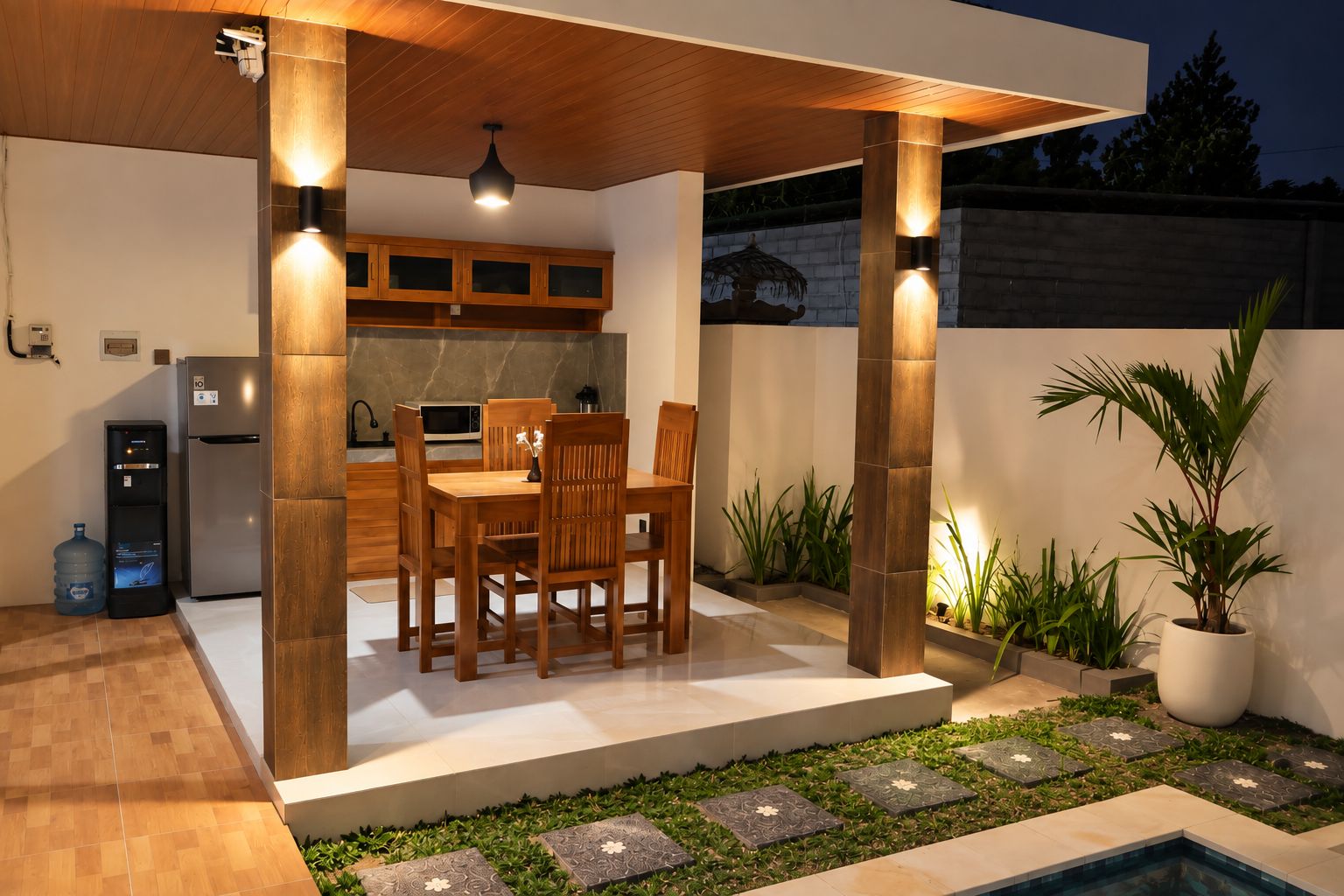 A covered outdoor dining area with a pool, surrounded by potted plants and a water feature.