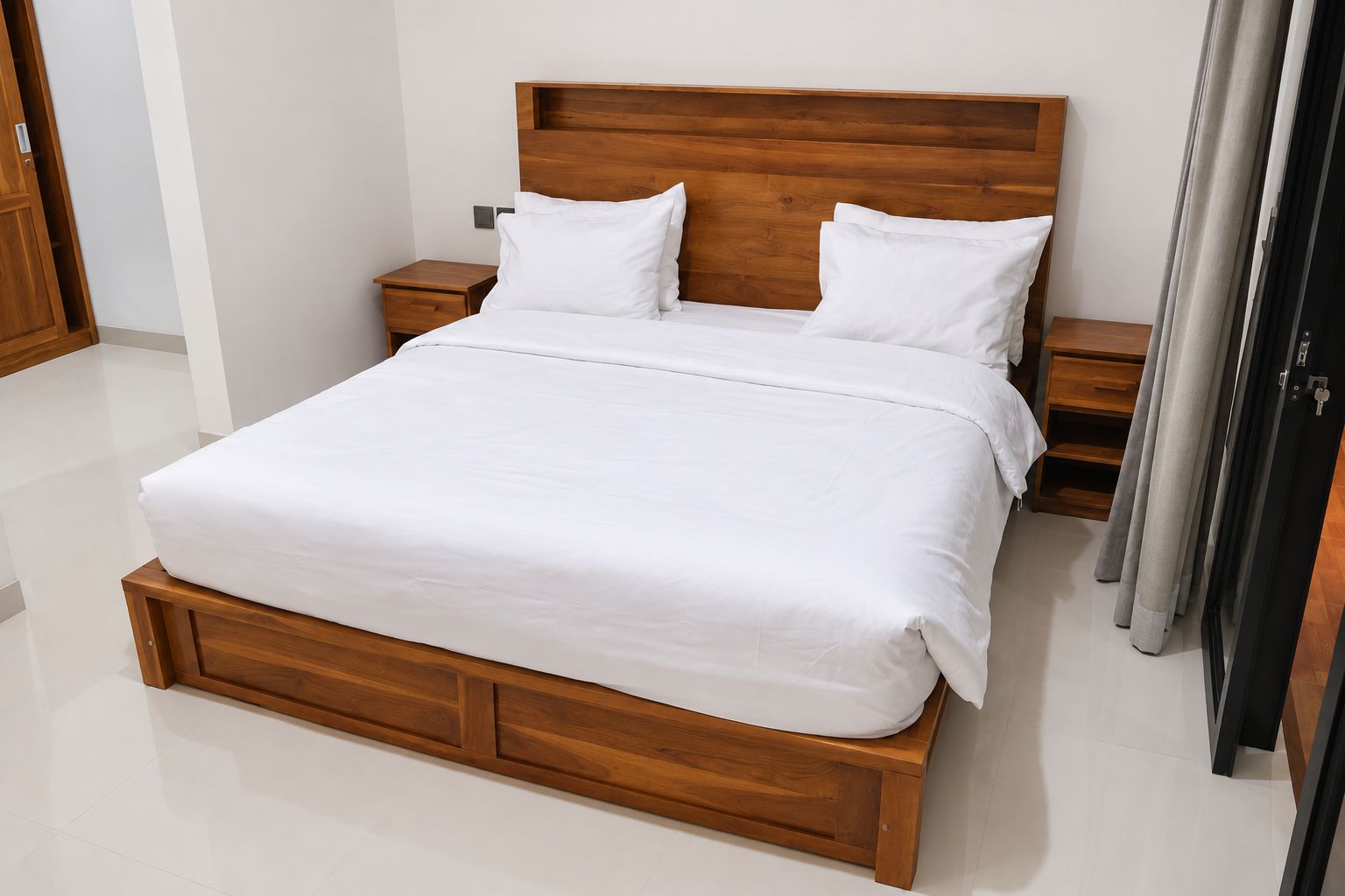 A modern bedroom with a wooden bed frame, white bedding, and a nightstand with a lamp.