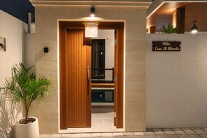 Entrada de un hotel con puerta de madera, un letrero que dice 'Villa Casa Il Mondo' y una planta en maceta a un lado.