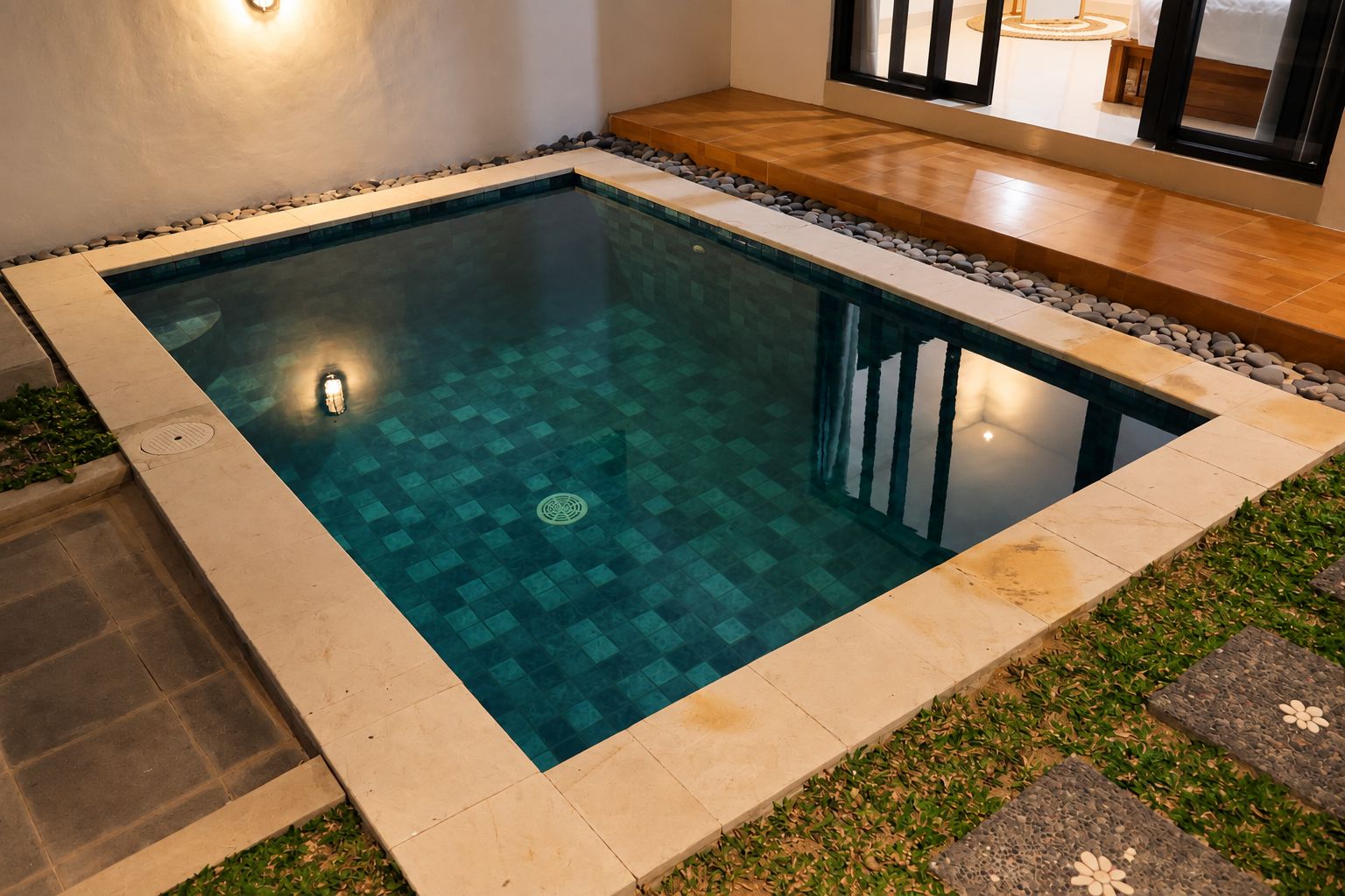 A rectangular swimming pool with a tiled border and a pebble bed.
