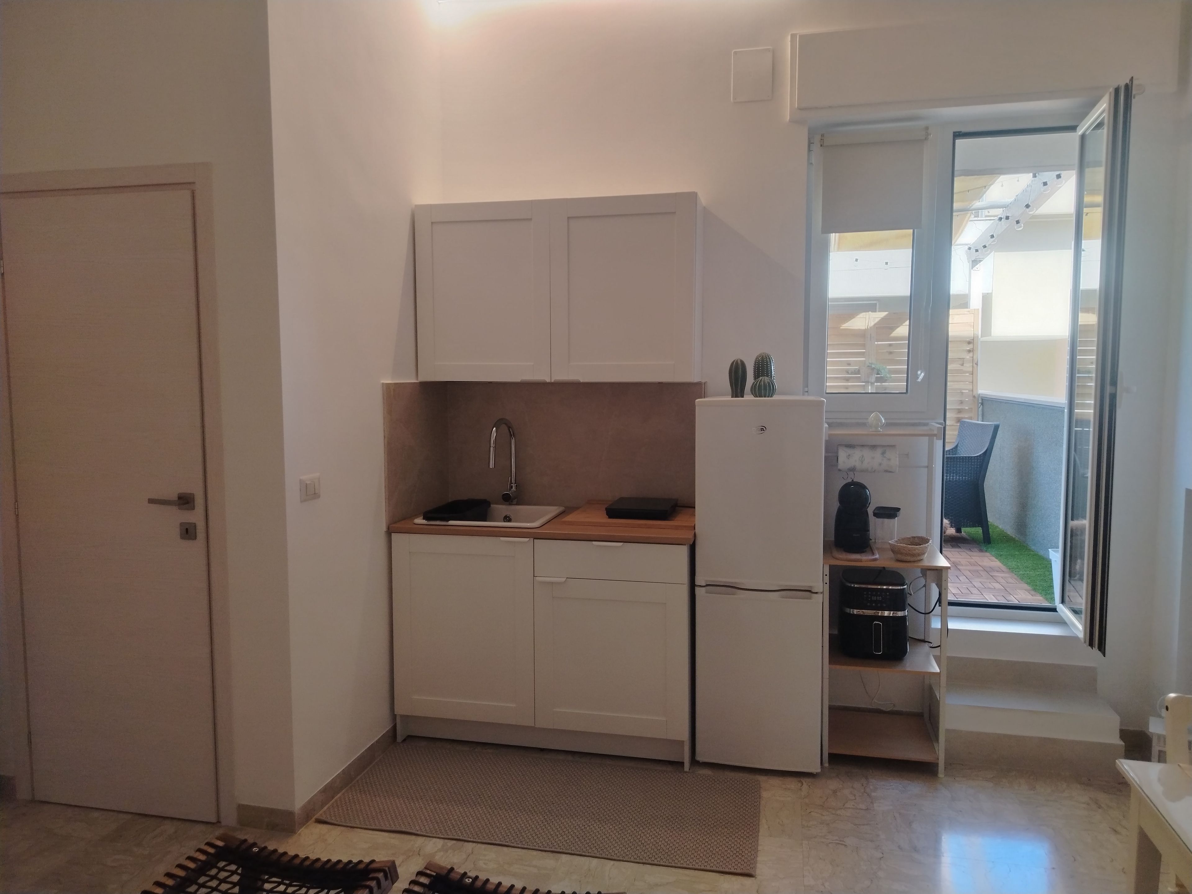 Eine kleine Küche mit Spüle, Schränken und Kühlschrank.