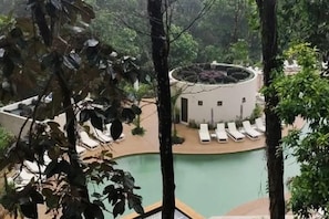 A pool area with lounge chairs and a circular building with a roof garden. - Hotel Gafsacomm Palenque (Palenque)