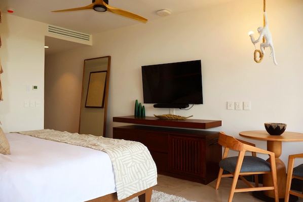A hotel room with a bed, a TV mounted on a wooden cabinet, a small round table with a bowl, and a ceiling fan. - Hotel Gafsacomm Palenque (Palenque)