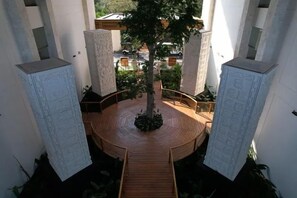 A circular wooden deck with a central tree, surrounded by white pillars with engraved designs. - Hotel Gafsacomm Palenque (Palenque)