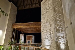 A modern interior with a wooden ceiling, a staircase, and intricate wall carvings.