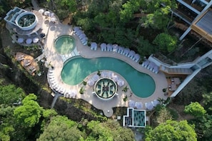 An aerial view of a resort with a large irregularly shaped pool surrounded by lounge areas and a circular water feature. - Hotel Gafsacomm Palenque (Palenque)