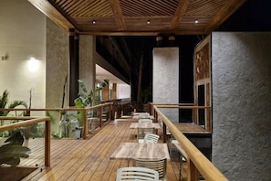 A wooden deck with tables and chairs, a railing, and a view of the interior. - Hotel Gafsacomm Palenque (Palenque)