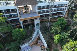 A multi-story hotel with a central tower, outdoor seating, and lush greenery.