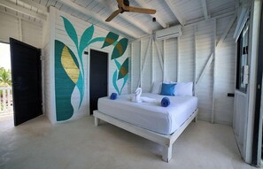 A bedroom with a bed, a ceiling fan, and a wall with a leaf design. - El Faro by OOL Hotels (Isla Holbox)