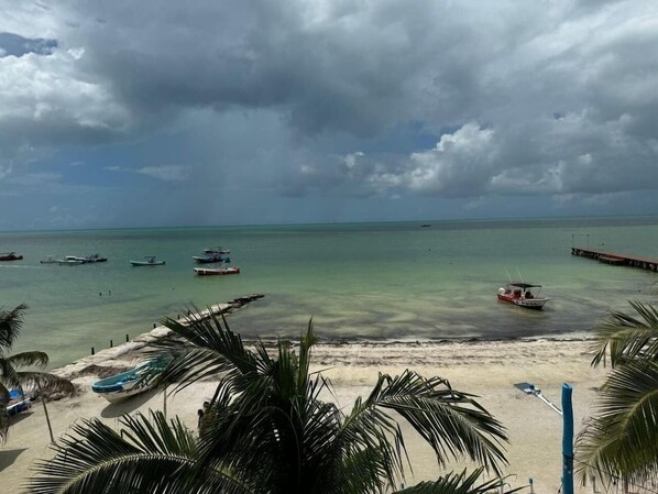 A beach with boats, a pier, and palm trees. - El Faro by OOL Hotels (Isla Holbox)