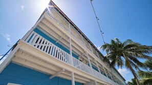 A multi-story building with balconies, a clear sky, and a palm tree. - El Faro by OOL Hotels (Isla Holbox)