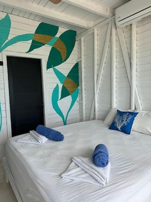A hotel room with a bed, a door, and a wall with a leaf pattern. - El Faro by OOL Hotels (Isla Holbox)
