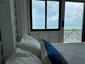 A bedroom with a bed, a window, and a view of the sea. - El Faro by OOL Hotels (Isla Holbox)