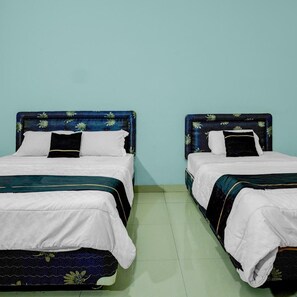 Zwei Betten mit je zwei Einzelbetten, mit blumengemusterten Kopfteilen und weißer Bettwäsche, vor einer hellblauen Wand.