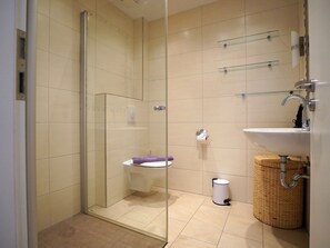 A modern bathroom with a glass-enclosed shower, a white sink, and a toilet. - Holiday Apartment With 1 Bedroom (Norden)