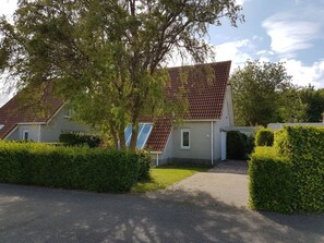 A residential building with a sloped roof, a paved driveway, and well-maintained hedges. - Strand4you Zeeland Village (Scharendijke)
