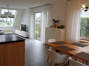 A modern kitchen with a dining area, a TV, and a plant. - Strand4you Zeeland Village (Scharendijke)
