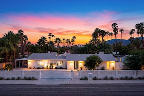 A two-story house with a covered patio and a view of palm trees and mountains. - Pool + Hot Tub + Game Room | Mtn Views + Fire Pit | The Royal Palms (Palm Springs)