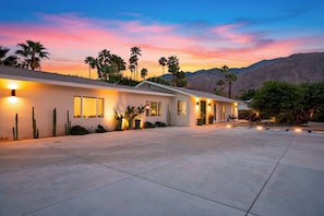 A modern two-story building with a flat roof, multiple windows, and a paved driveway. - Pool + Hot Tub + Game Room | Mtn Views + Fire Pit | The Royal Palms (Palm Springs)