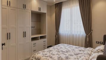 Ein Schlafzimmer mit einem Bett, einem Kleiderschrank und einem Fenster mit Vorhängen.