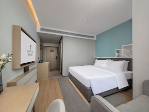 A hotel room with a bed, a desk, a chair, a TV, and a door leading to a bathroom. - Country Inn & Suites Huashi Metro (Guangzhou)