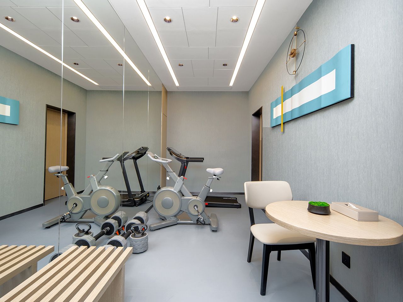 Une salle de sport équipée de matériel d’exercice, avec une table et des chaises.