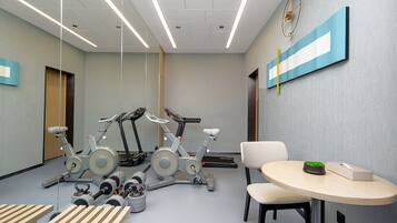 Une salle de sport équipée de matériel d’exercice, avec une table et des chaises.
