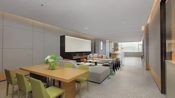 A modern office space with a long table, green chairs, a sofa, and a fireplace.